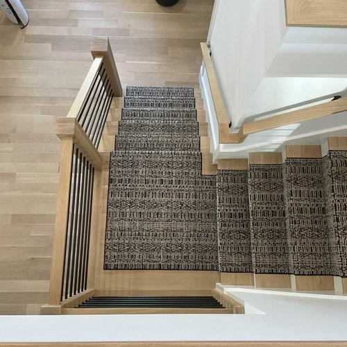 Custom stair runner installation by Sunshine Carpet & Flooring in North Chelmsford, MA – classic patterned runner on hardwood stairs