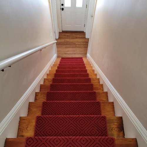 Custom stair runner installation by Sunshine Carpet & Flooring in North Chelmsford, MA – classic patterned runner on hardwood stairs