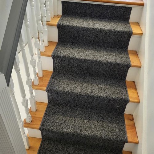 Custom stair runner installation by Sunshine Carpet & Flooring in North Chelmsford, MA – classic patterned runner on hardwood stairs
