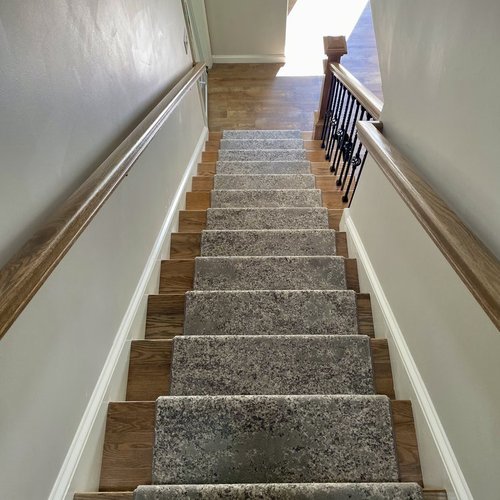 Custom stair runner installation by Sunshine Carpet & Flooring in North Chelmsford, MA – classic patterned runner on hardwood stairs