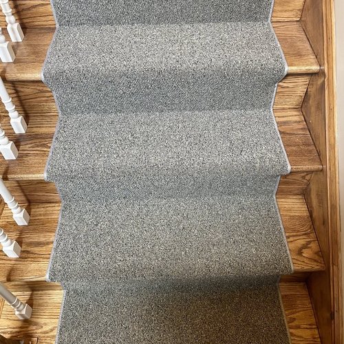 Custom stair runner installation by Sunshine Carpet & Flooring in North Chelmsford, MA – classic patterned runner on hardwood stairs
